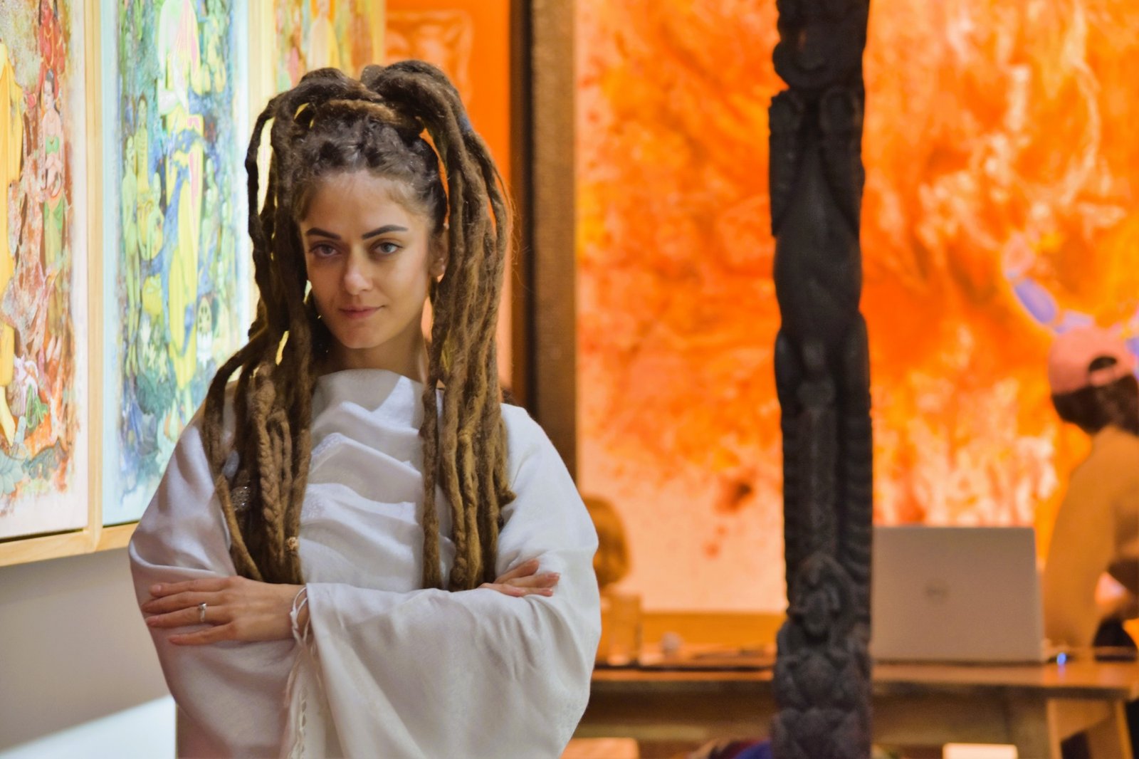 Christina standing in front of her paintings at an art gallery exhibition